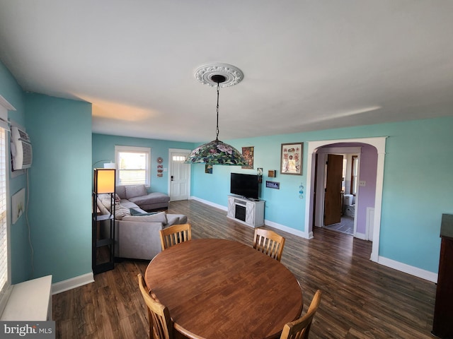 dining space with arched walkways, a wall unit AC, dark wood-style floors, and baseboards