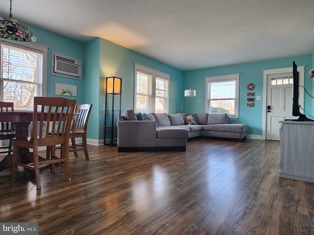 living area with an AC wall unit, dark wood finished floors, and baseboards