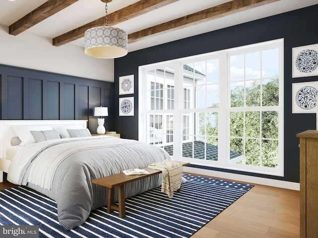 bedroom with multiple windows, beamed ceiling, a decorative wall, and wood finished floors