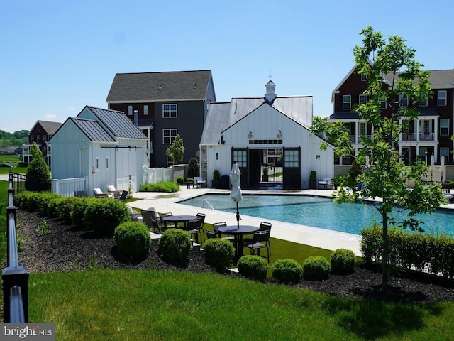 pool featuring an outbuilding, a lawn, a patio area, and fence