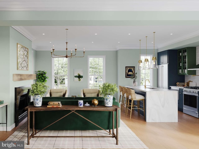 living room featuring light wood-style floors, a fireplace, a chandelier, and crown molding