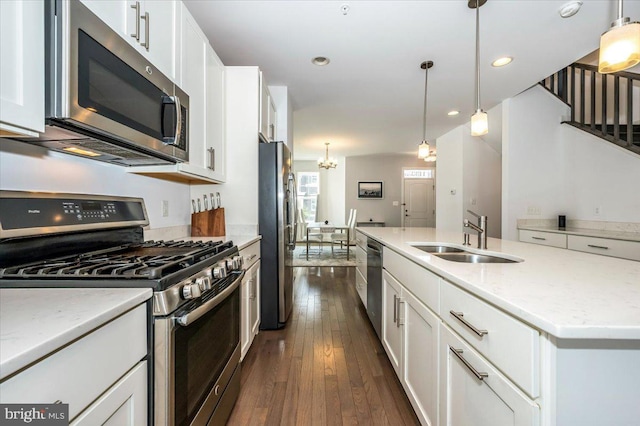 kitchen featuring a sink, stainless steel appliances, white cabinets, dark wood-style flooring, and hanging light fixtures