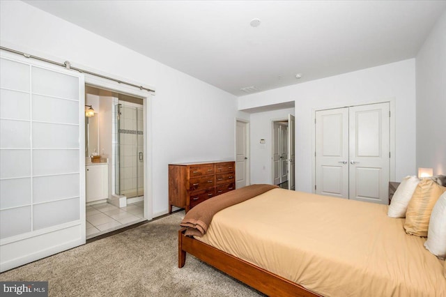 bedroom with visible vents, ensuite bath, a closet, a barn door, and carpet flooring