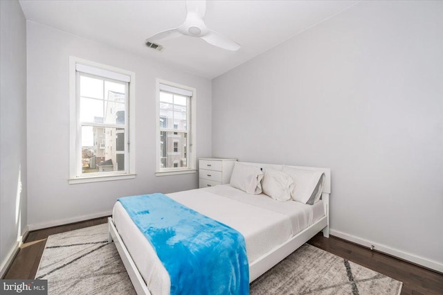 bedroom with ceiling fan, visible vents, baseboards, and wood finished floors