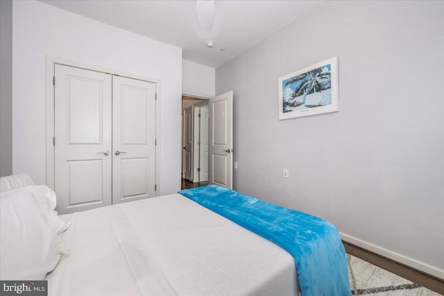 bedroom with wood finished floors, baseboards, and a closet