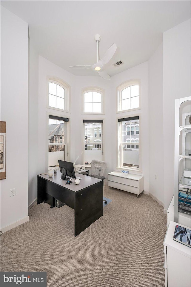 office area featuring light carpet, a healthy amount of sunlight, visible vents, and ceiling fan