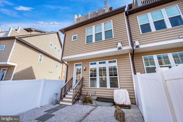 back of property featuring entry steps and fence