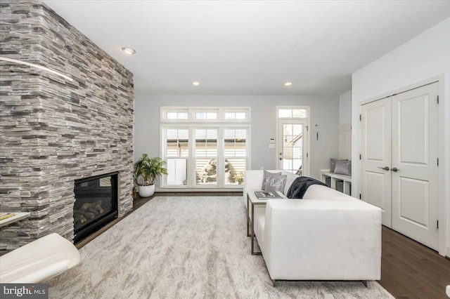 living room featuring recessed lighting, a large fireplace, and wood finished floors