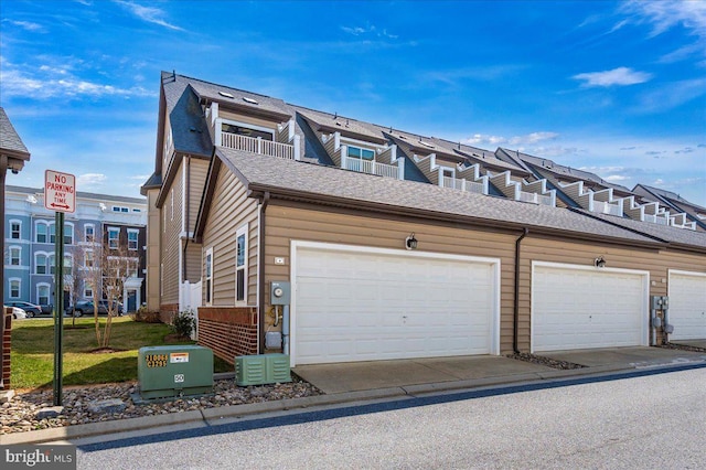 view of side of home featuring community garages and a shingled roof