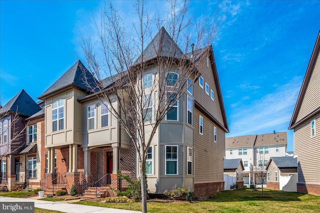 view of front of house featuring a front lawn, brick siding, a residential view, and stucco siding