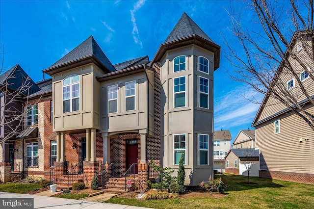 view of front facade with stucco siding, a residential view, a front yard, a shingled roof, and brick siding