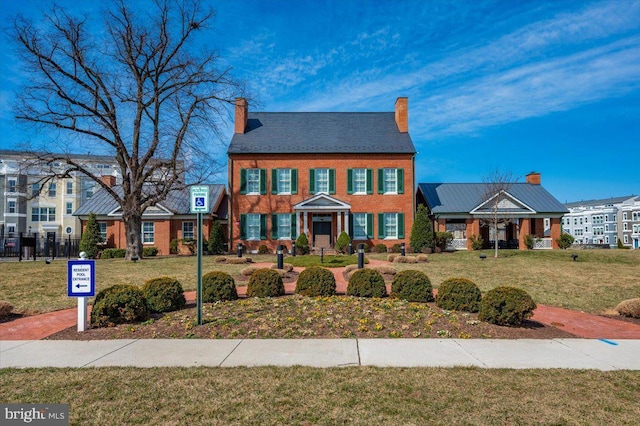 view of front of property with brick siding, a chimney, a front lawn, and fence