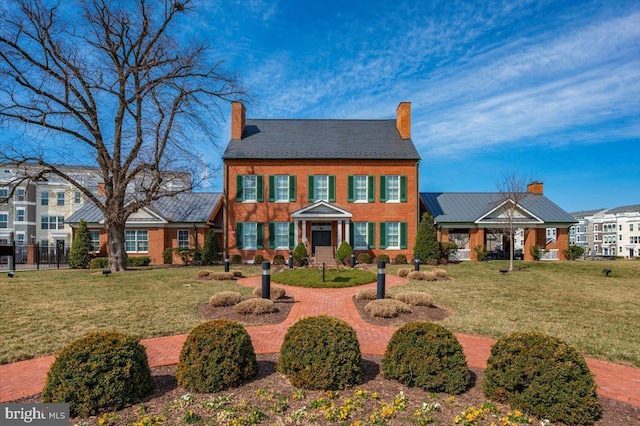 view of front facade with a chimney, a front yard, and fence