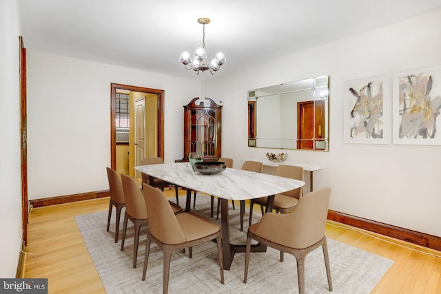 dining area with a chandelier, light wood finished floors, and baseboards