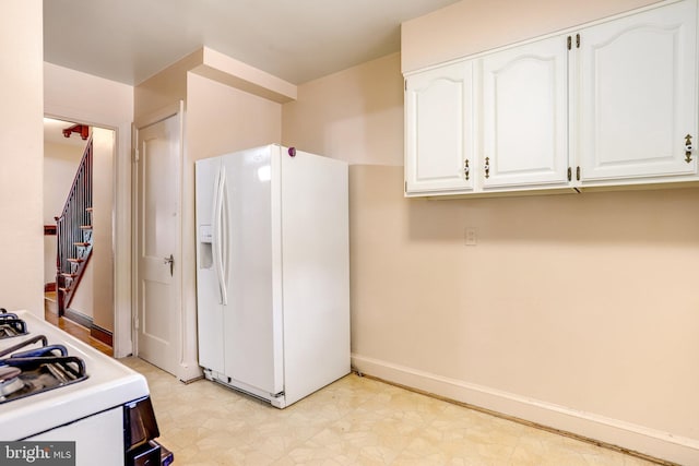 kitchen featuring white appliances, baseboards, white cabinetry, and light floors