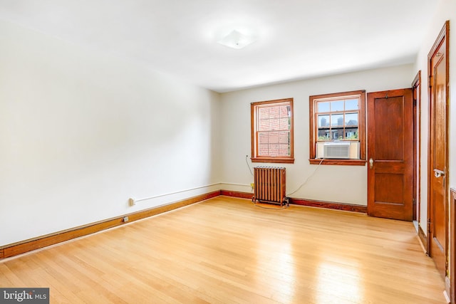 unfurnished room featuring light wood-type flooring, baseboards, and radiator heating unit