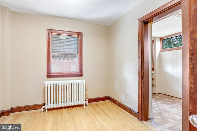 unfurnished room featuring radiator, baseboards, and wood finished floors