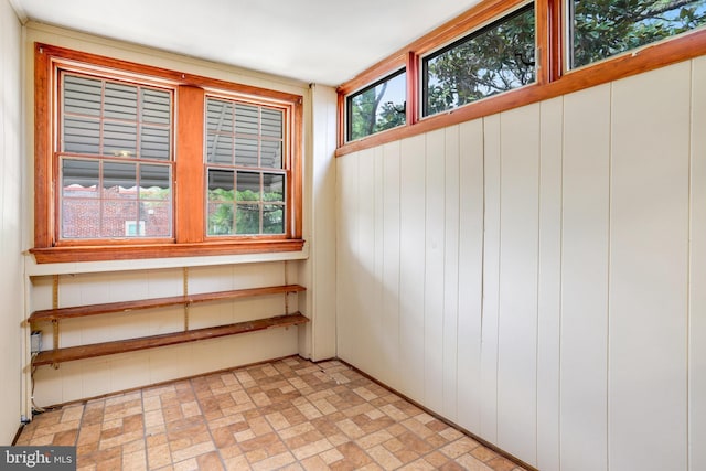 unfurnished room featuring brick floor and wood walls