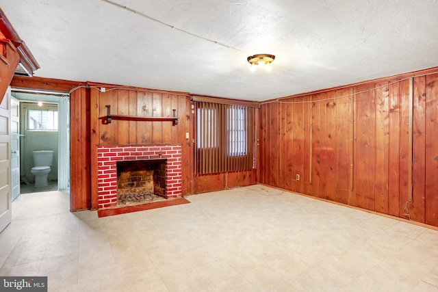 unfurnished living room featuring a brick fireplace, tile patterned floors, and wood walls