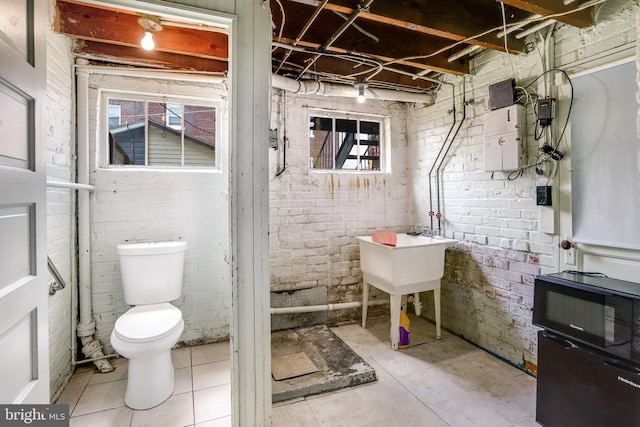 bathroom with brick wall and toilet