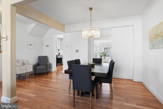 dining room featuring light wood finished floors, an inviting chandelier, and baseboards