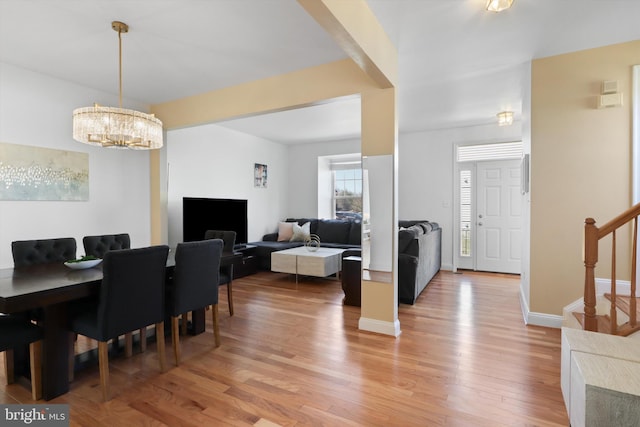 dining space featuring a notable chandelier, stairway, light wood-type flooring, and baseboards