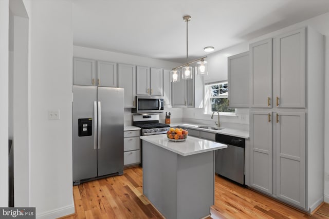 kitchen featuring gray cabinets, a sink, a kitchen island, stainless steel appliances, and light countertops