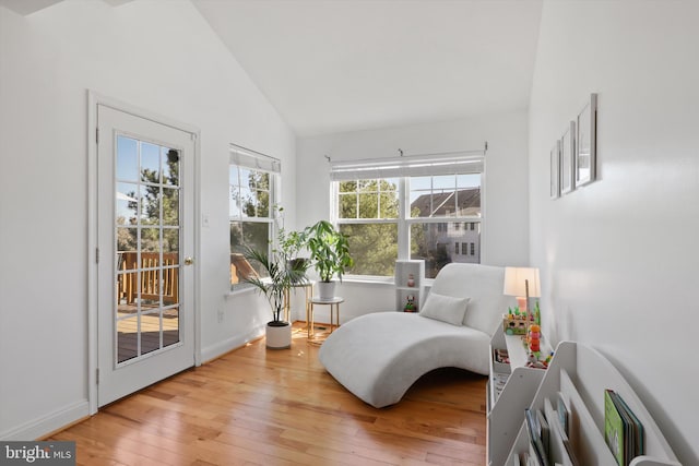 living area featuring vaulted ceiling, baseboards, and wood-type flooring