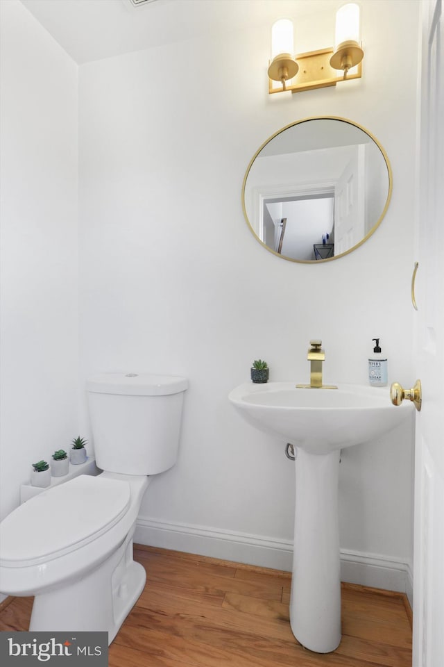 bathroom with toilet, wood finished floors, and baseboards