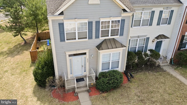 view of front of home with a standing seam roof, a shingled roof, a front yard, and metal roof