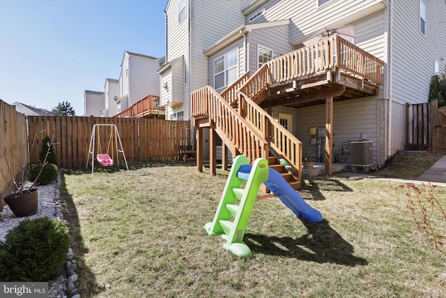 view of jungle gym with a yard, a deck, central AC unit, and a fenced backyard