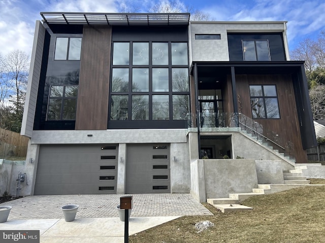 contemporary home with an attached garage, driveway, and stairs