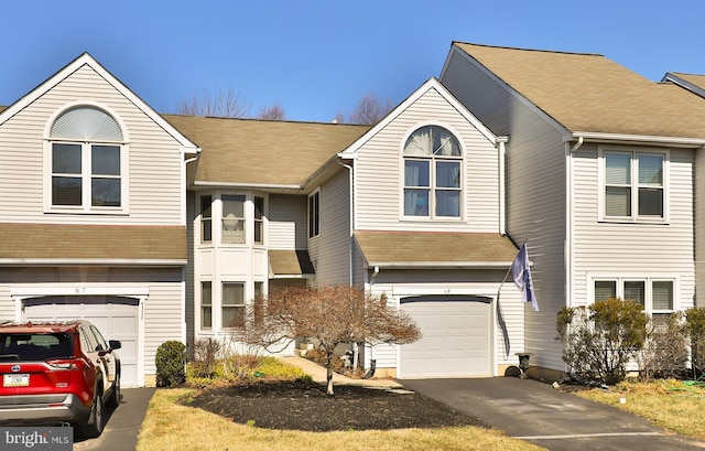 multi unit property with driveway, a garage, and roof with shingles