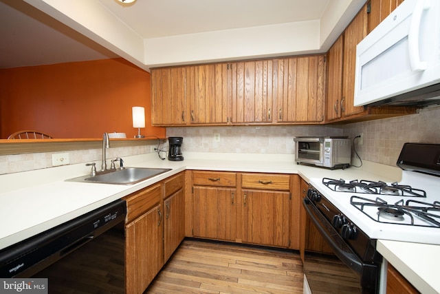 kitchen with white microwave, a sink, range with gas stovetop, black dishwasher, and light countertops