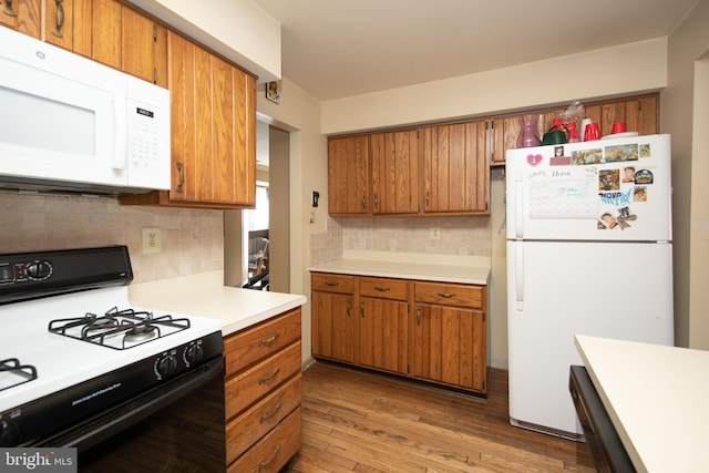 kitchen with white appliances, light countertops, and brown cabinetry