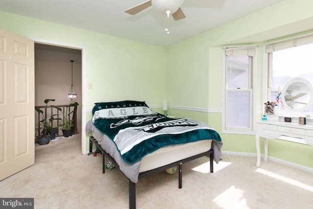 bedroom with a ceiling fan, light carpet, and baseboards