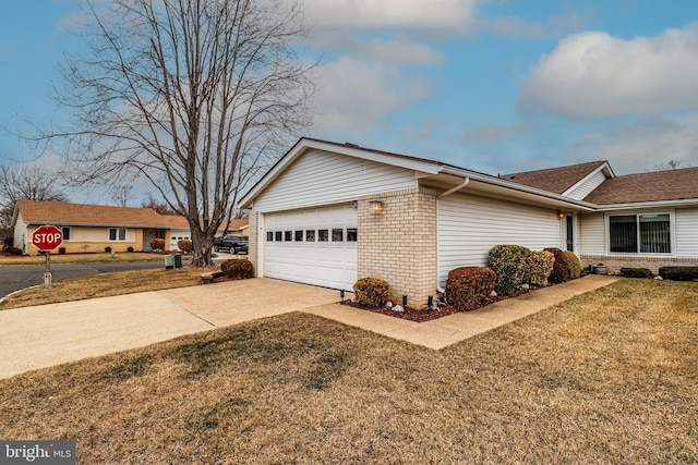 view of side of property with a garage, concrete driveway, brick siding, and a yard