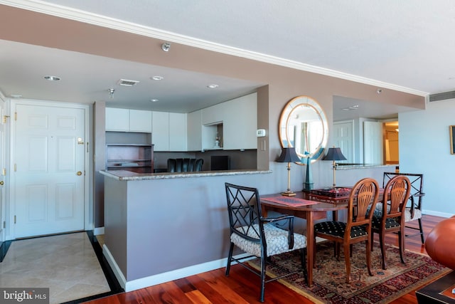 dining room with wood finished floors, visible vents, and crown molding