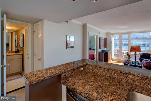 kitchen with open floor plan, ornamental molding, dark stone countertops, and a sink