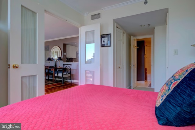 bedroom featuring wood finished floors, visible vents, and crown molding