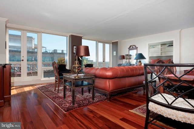 living area featuring crown molding, built in shelves, and wood finished floors