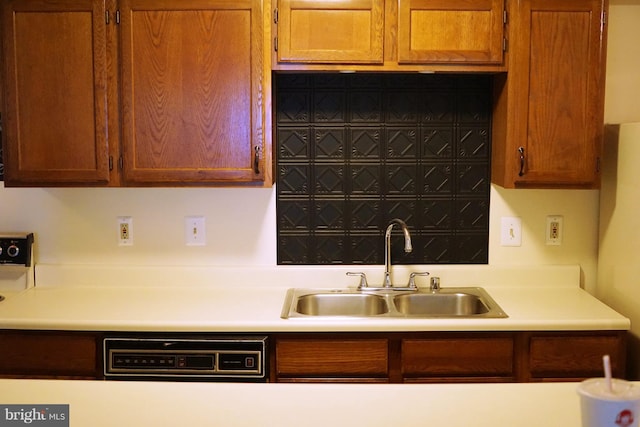 kitchen featuring brown cabinetry, light countertops, and a sink