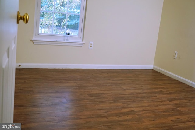 spare room with dark wood-type flooring and baseboards