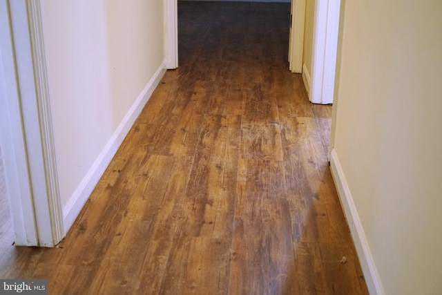 corridor with baseboards and hardwood / wood-style floors