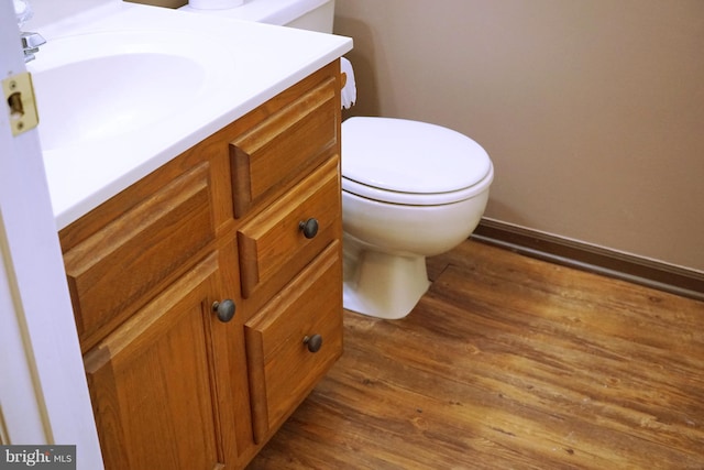 bathroom with toilet, wood finished floors, vanity, and baseboards