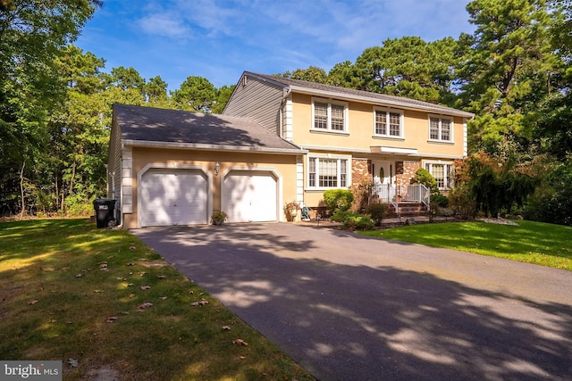 colonial house featuring aphalt driveway, an attached garage, brick siding, stucco siding, and a front lawn