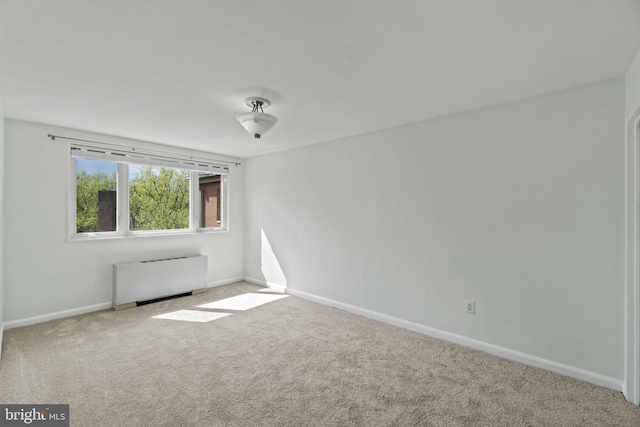 carpeted empty room with radiator heating unit and baseboards