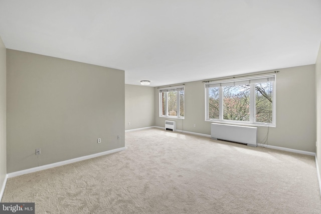 unfurnished living room with baseboards, carpet, and radiator