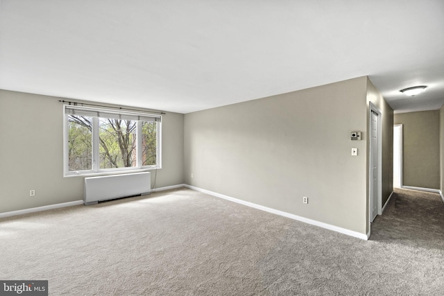 empty room with carpet, radiator heating unit, and baseboards