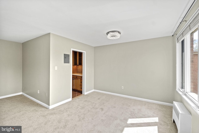 unfurnished bedroom with carpet floors, electric panel, baseboards, and radiator heating unit